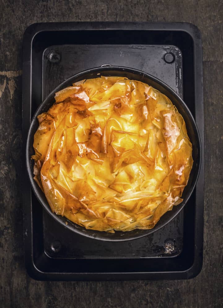 golden Filo pastry pie on black baking tray, top view