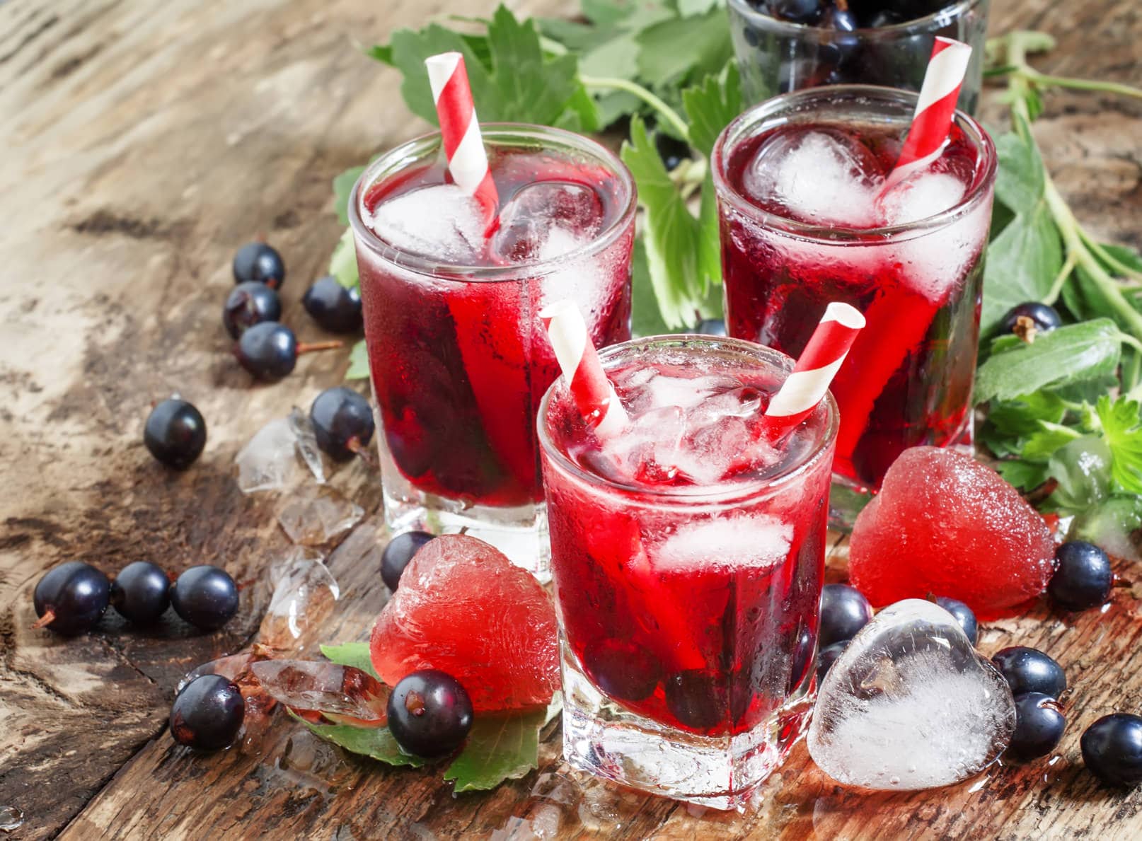 Fresh blackcurrant drink with berries and ice in a heart shape, selective focus